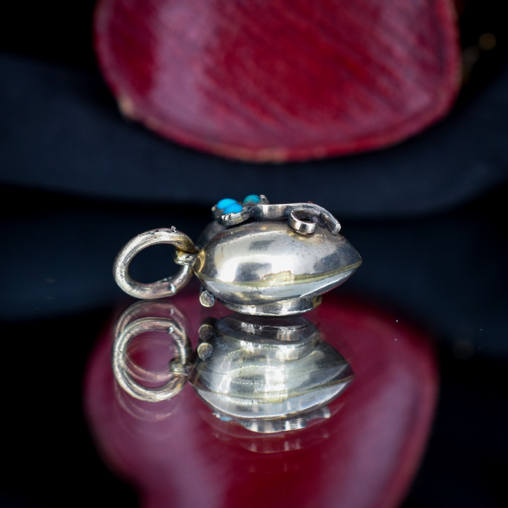 A heart-shaped gold pendant decorated with a raised stem motif set with three round blue turquoise cabochons in a floral pattern. View VIII