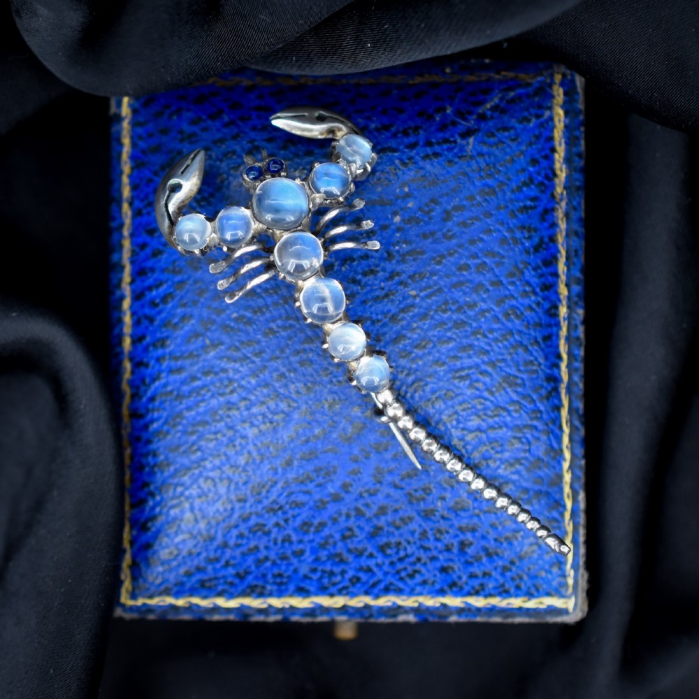 An Edwardian sterling silver brooch designed in the shape of a scorpion, featuring cabochon moonstones along its body and small blue stones for eyes. View II