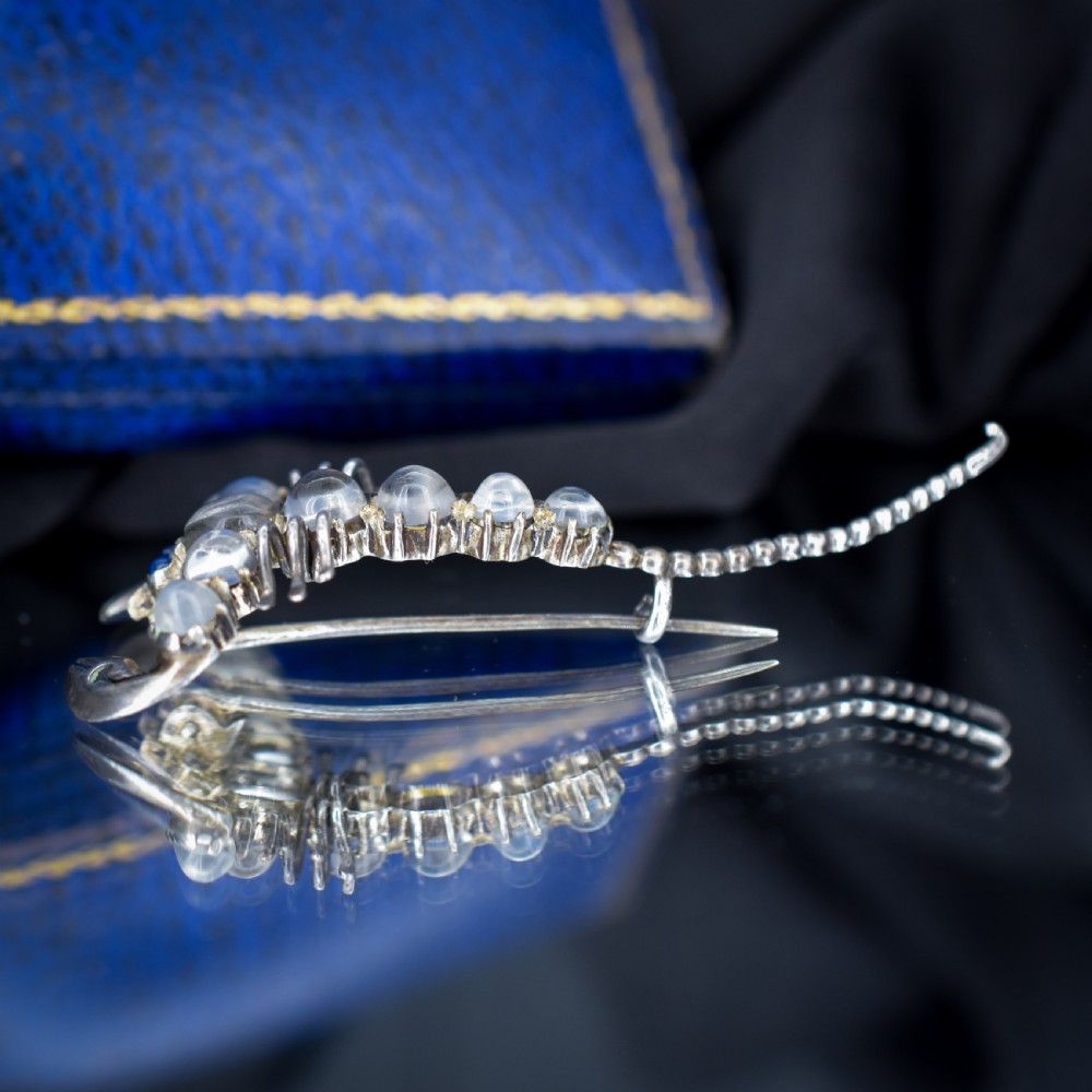 An Edwardian sterling silver brooch designed in the shape of a scorpion, featuring cabochon moonstones along its body and small blue stones for eyes. View VII