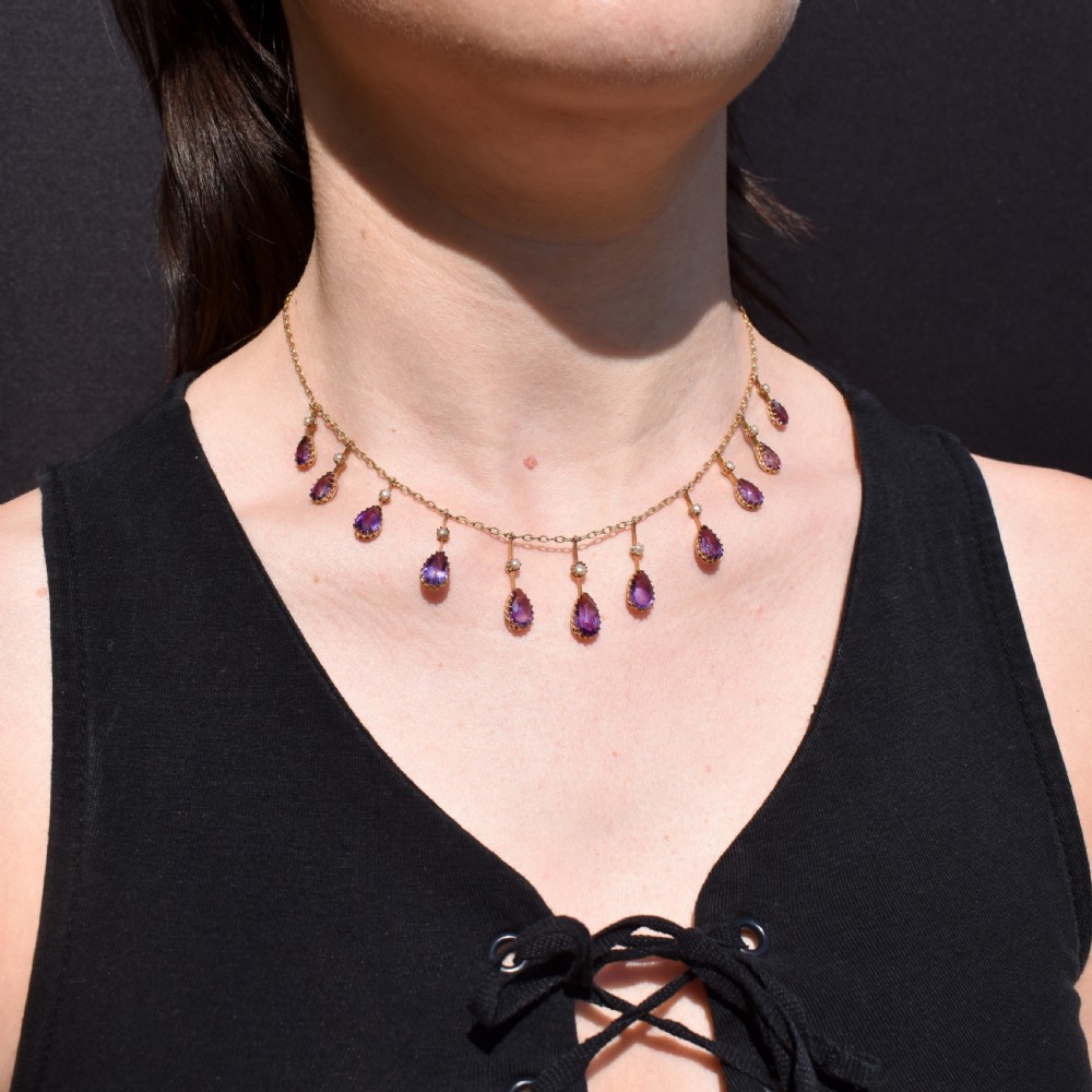 An antique gold fringe necklace featuring suspended pear-cut amethyst drops and seed pearls. View II