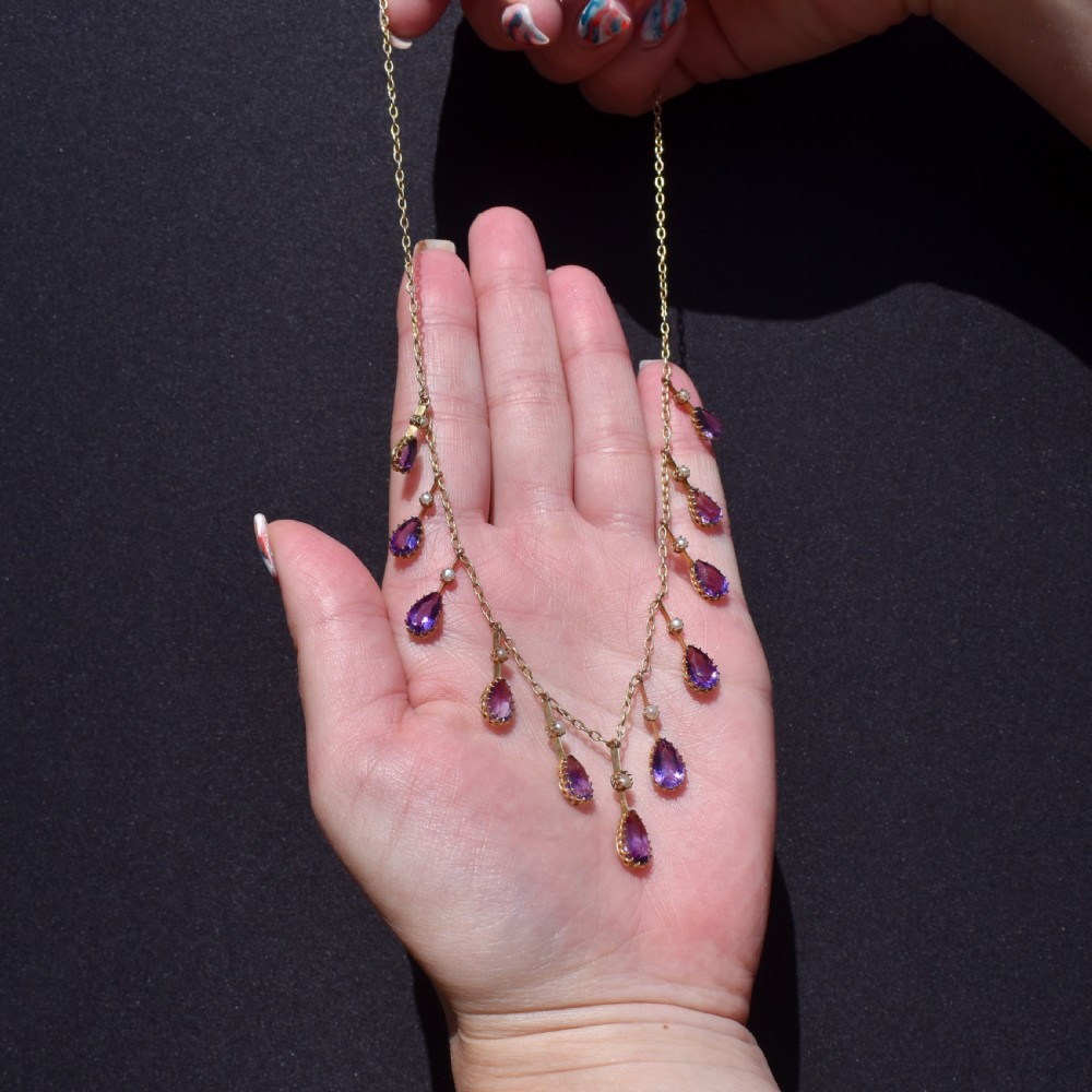 An antique gold fringe necklace featuring suspended pear-cut amethyst drops and seed pearls. View VII