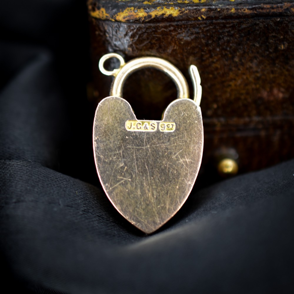 An Edwardian 9ct gold heart-shaped padlock pendant featuring four gold screw accents, a central keyhole, a top shackle catch, and a jump ring. View II