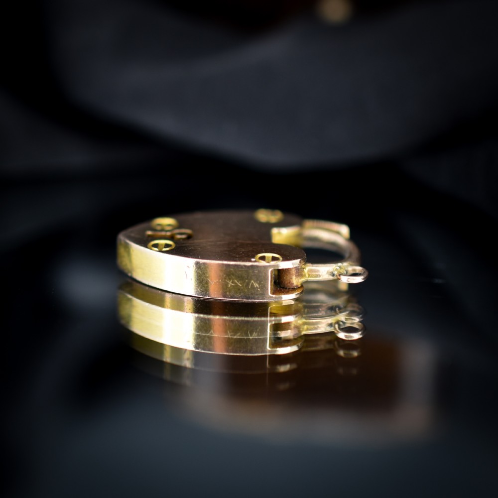 An Edwardian 9ct gold heart-shaped padlock pendant featuring four gold screw accents, a central keyhole, a top shackle catch, and a jump ring. View IV