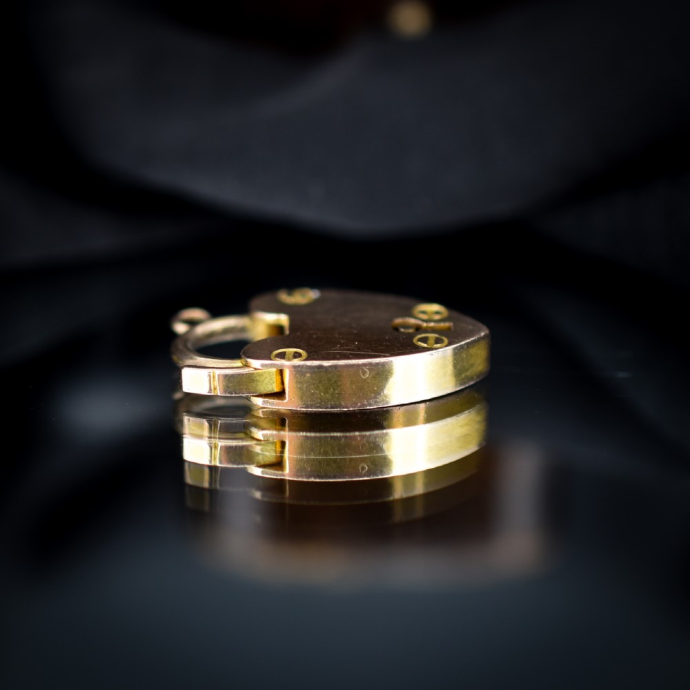 An Edwardian 9ct gold heart-shaped padlock pendant featuring four gold screw accents, a central keyhole, a top shackle catch, and a jump ring. View V