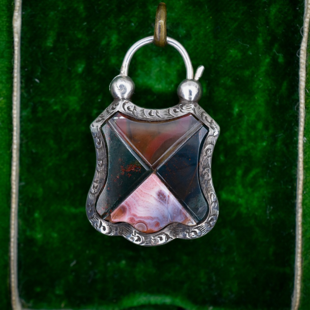 A Victorian silver padlock-shaped pendant featuring inlaid segments of red, green, and patterned agate with hand-engraved floral borders. View II