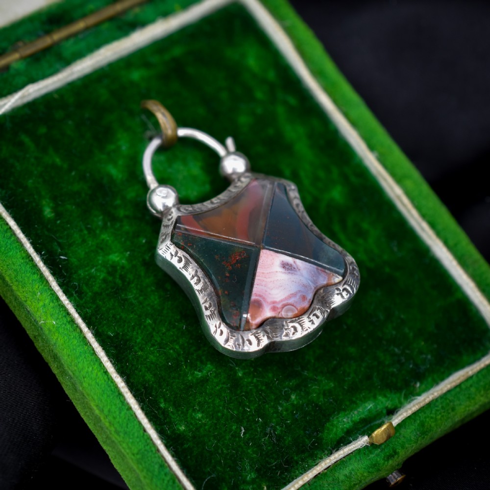 A Victorian silver padlock-shaped pendant featuring inlaid segments of red, green, and patterned agate with hand-engraved floral borders. View III
