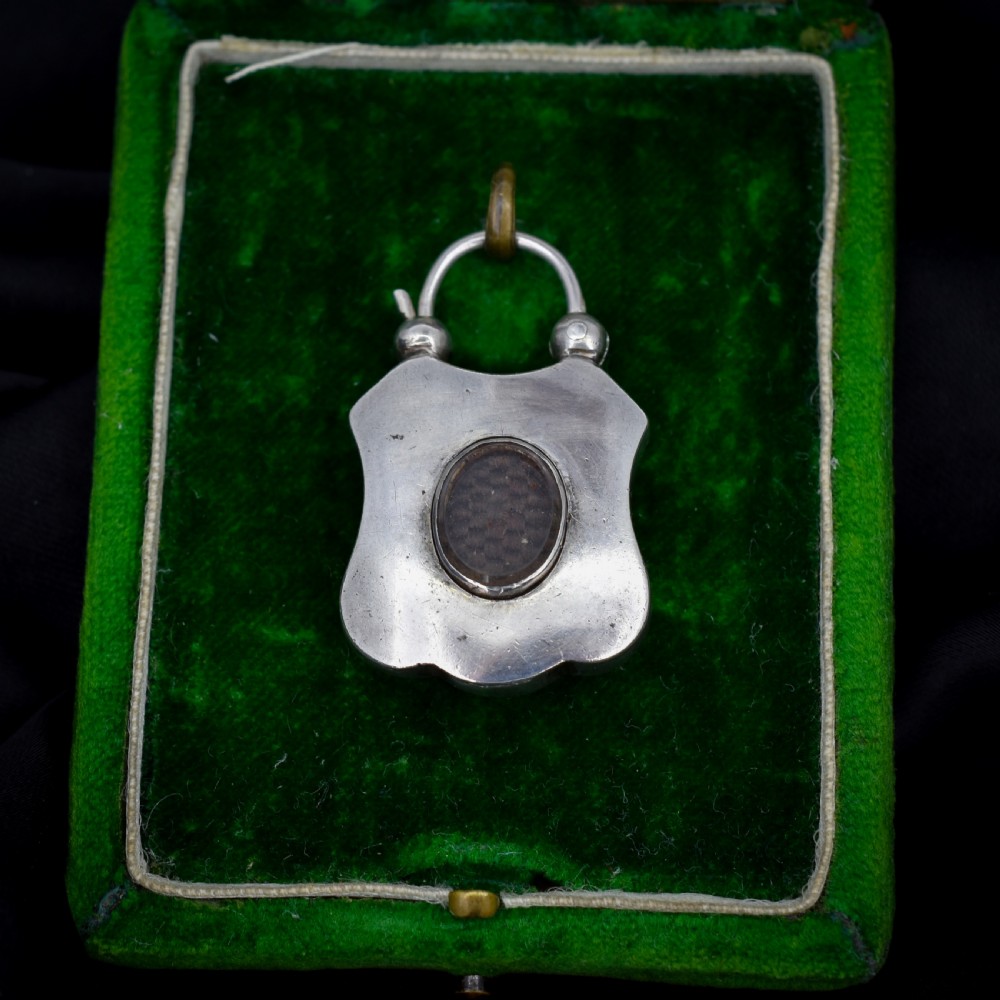 A Victorian silver padlock-shaped pendant featuring inlaid segments of red, green, and patterned agate with hand-engraved floral borders. View IV