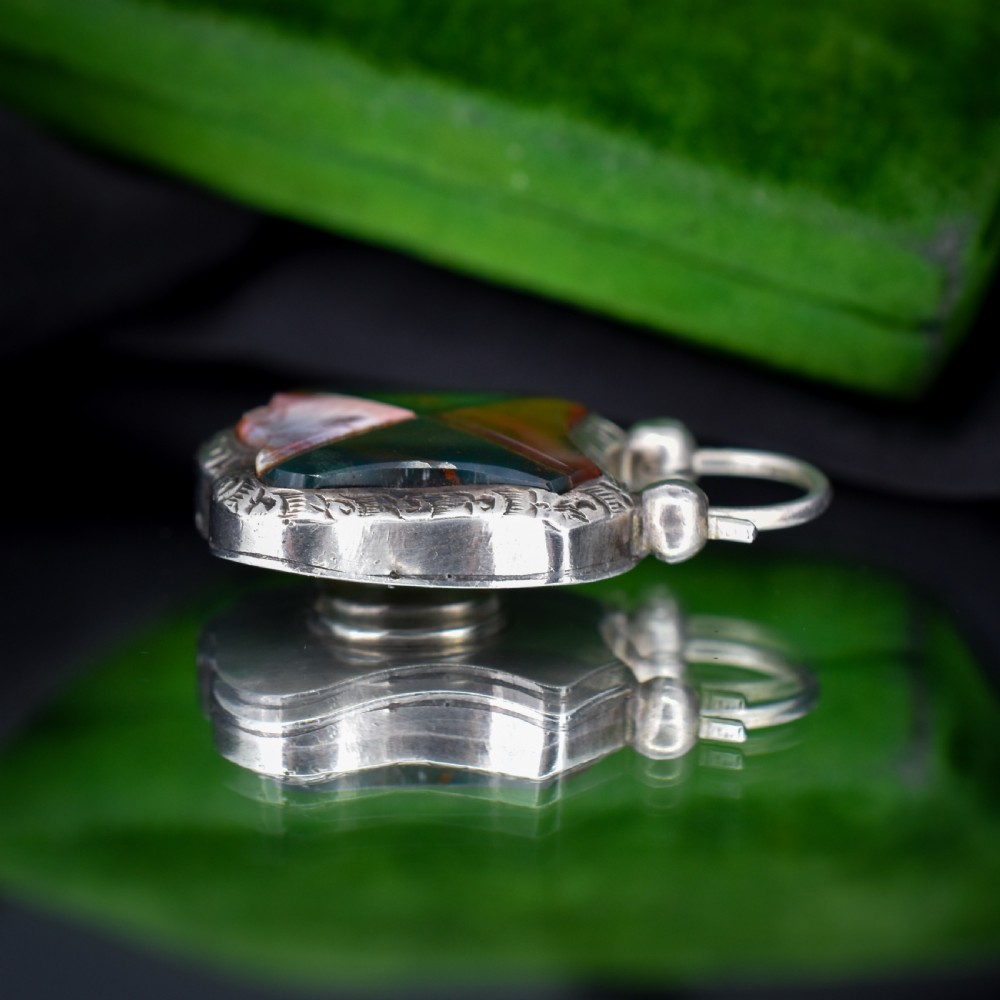 A Victorian silver padlock-shaped pendant featuring inlaid segments of red, green, and patterned agate with hand-engraved floral borders. View VI