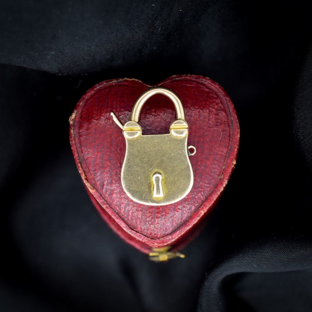 An antique 9ct yellow gold opening purse-style padlock charm featuring a keyhole motif and a hinged shackle.