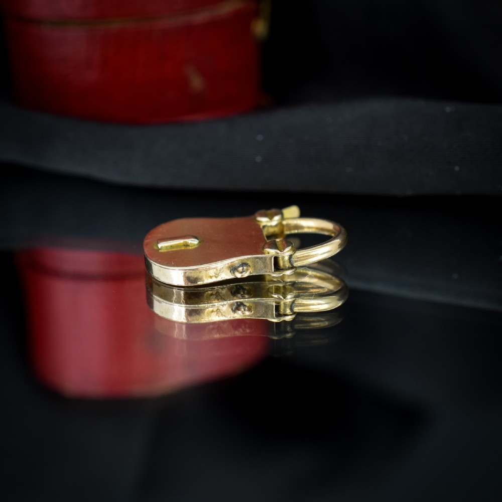 An antique 9ct yellow gold opening purse-style padlock charm featuring a keyhole motif and a hinged shackle. View V