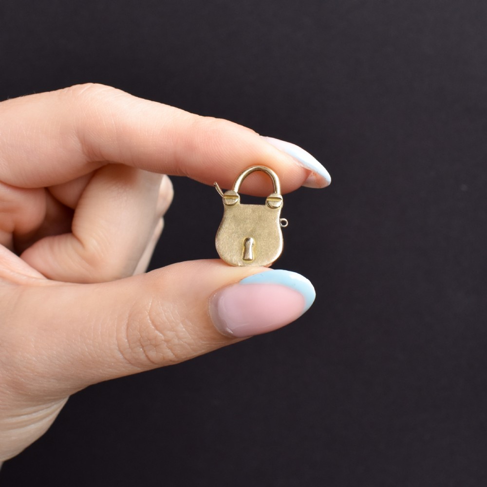 An antique 9ct yellow gold opening purse-style padlock charm featuring a keyhole motif and a hinged shackle. View VIII