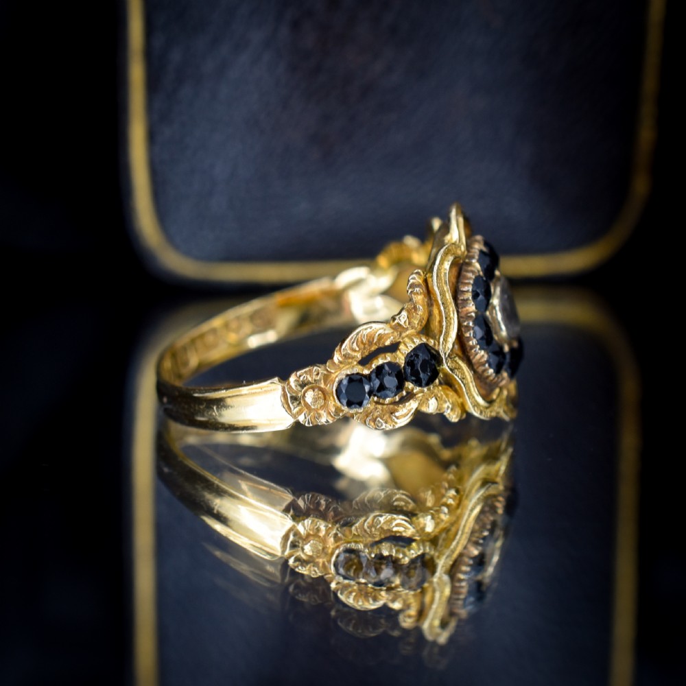 A Georgian gold ring featuring a central woven hair panel set under glass, surrounded by a cluster of faceted black jet stones. View V