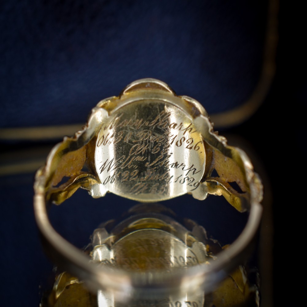A Georgian gold ring featuring a central woven hair panel set under glass, surrounded by a cluster of faceted black jet stones. View VI