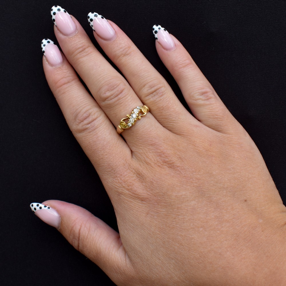 An 18ct yellow gold ring set with five graduated old-cut diamonds across a carved scrollwork band. View II