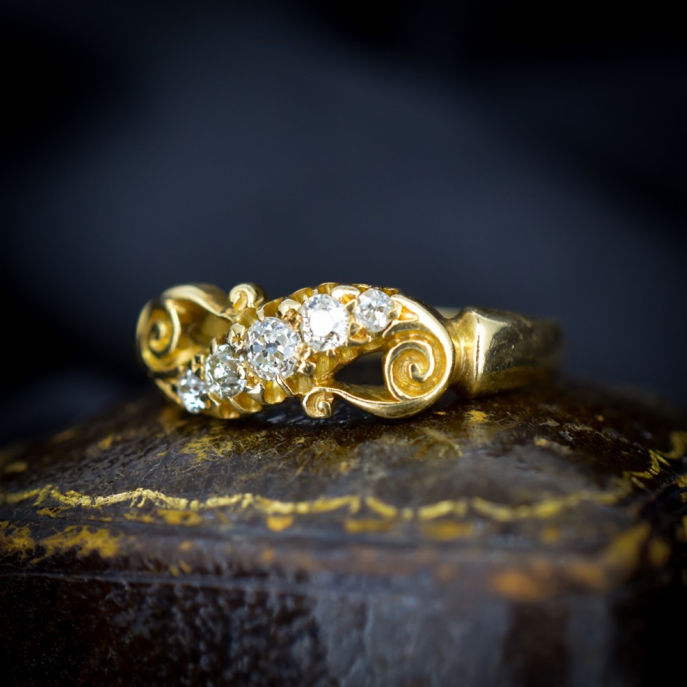 An 18ct yellow gold ring set with five graduated old-cut diamonds across a carved scrollwork band. View III