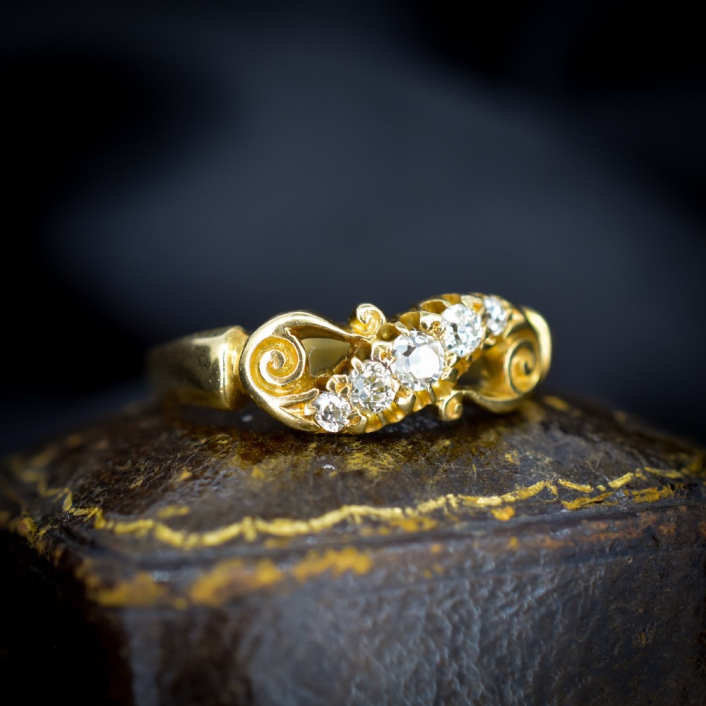 An 18ct yellow gold ring set with five graduated old-cut diamonds across a carved scrollwork band. View V