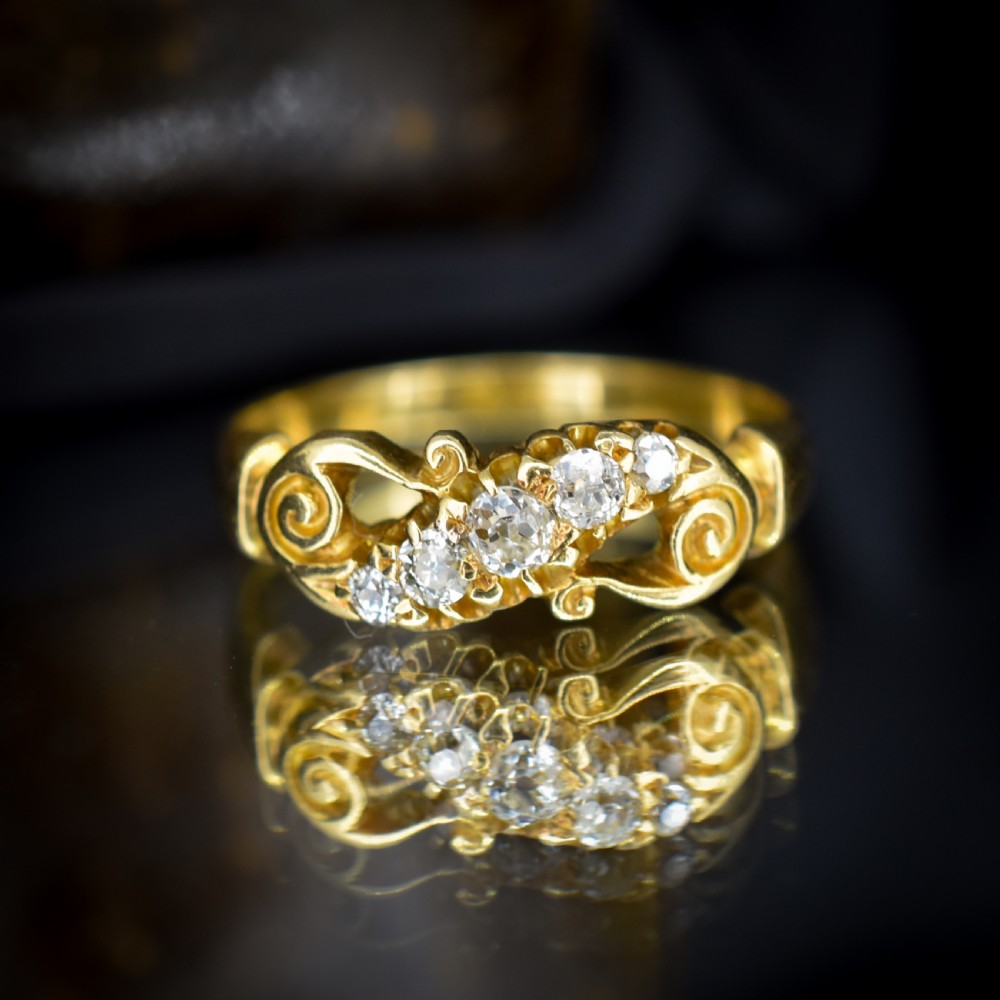 An 18ct yellow gold ring set with five graduated old-cut diamonds across a carved scrollwork band. View VII