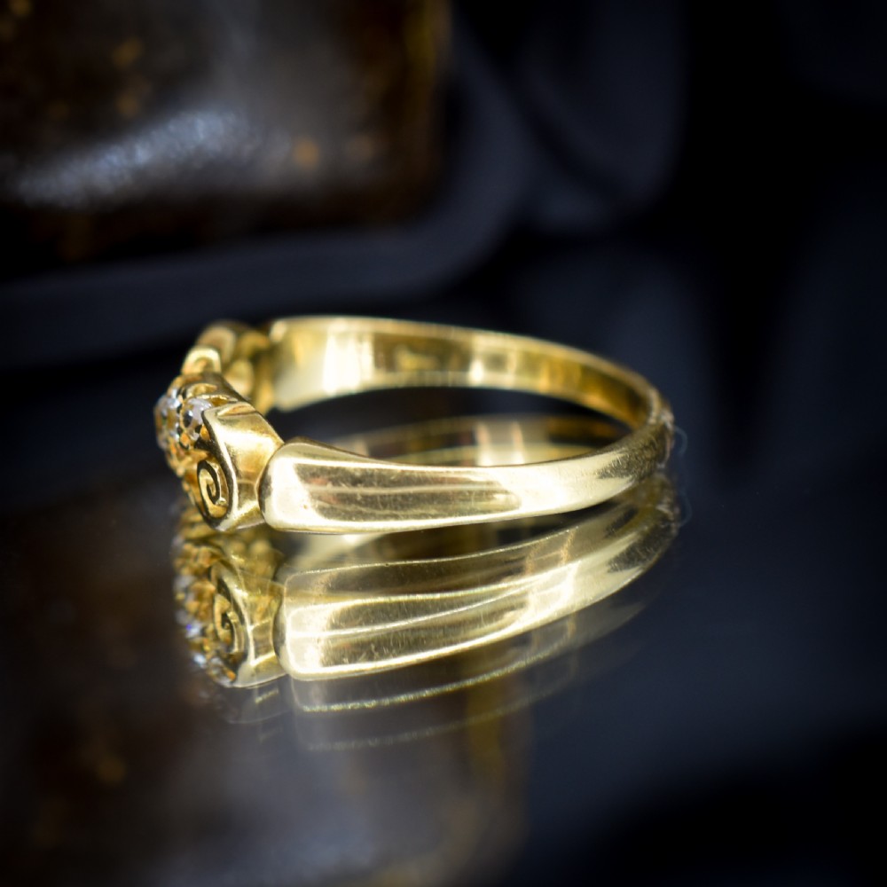 An 18ct yellow gold ring set with five graduated old-cut diamonds across a carved scrollwork band. View VIII