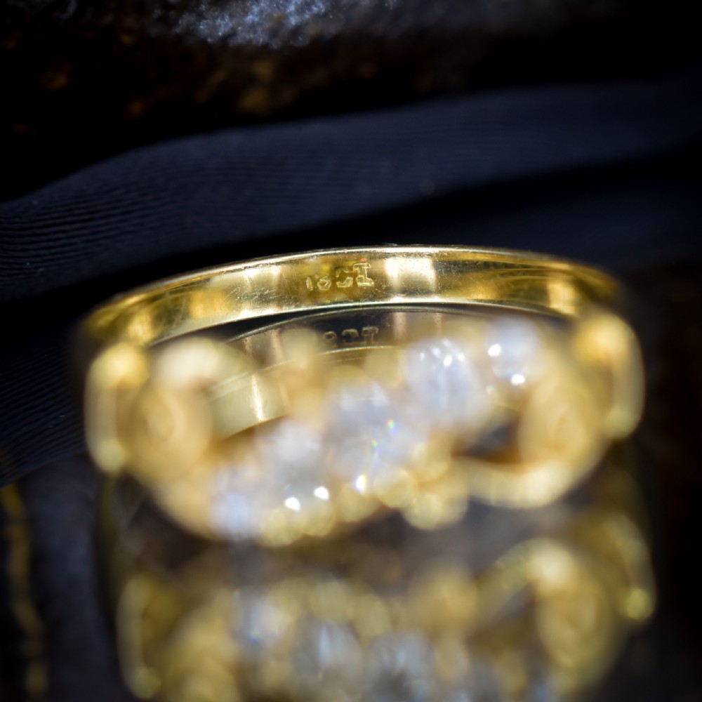 An 18ct yellow gold ring set with five graduated old-cut diamonds across a carved scrollwork band. View X