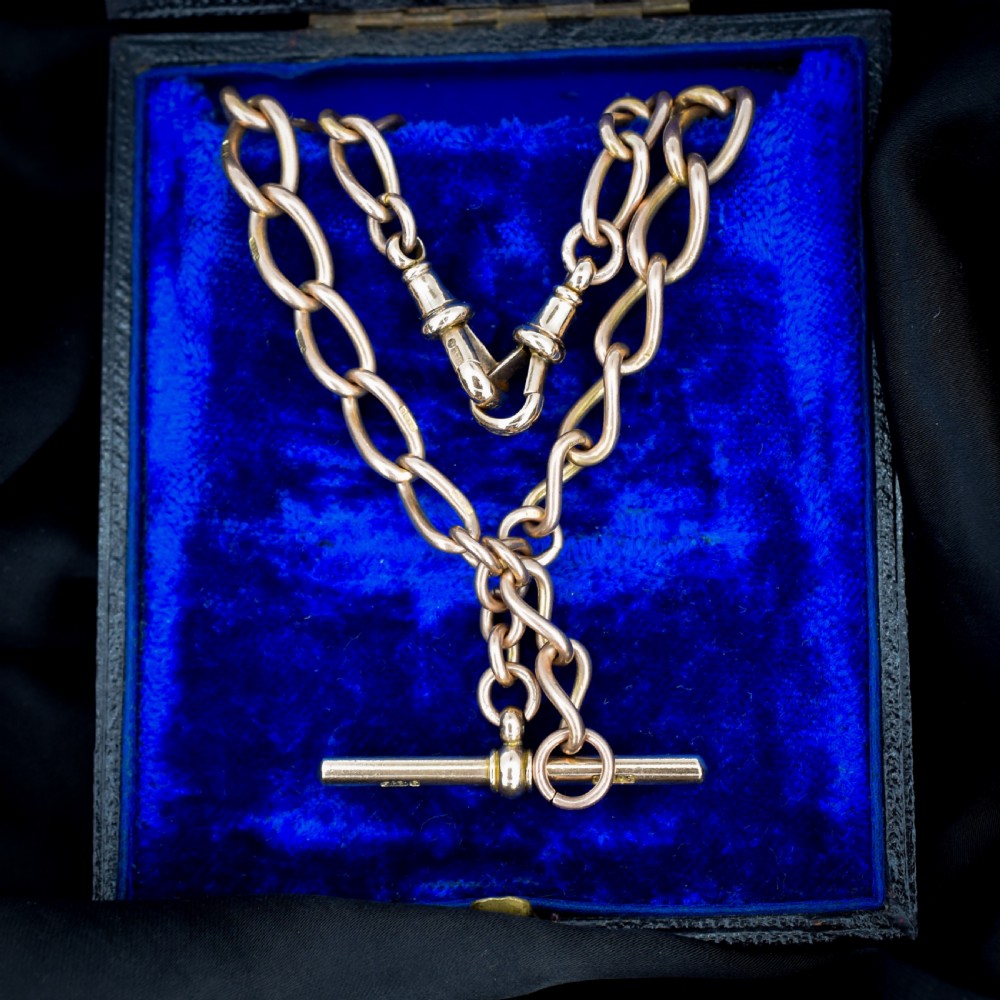 An antique 9ct gold Albert watch chain featuring oval links, a central T-bar, and double dog clip clasps.