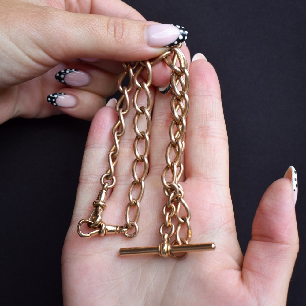 An antique 9ct gold Albert watch chain featuring oval links, a central T-bar, and double dog clip clasps. View X