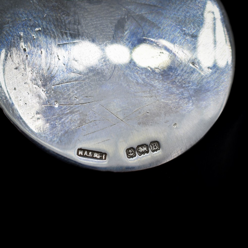 A circular silver Art Deco medallion depicting two football players in relief with a football, suspended from a top loop. View VI
