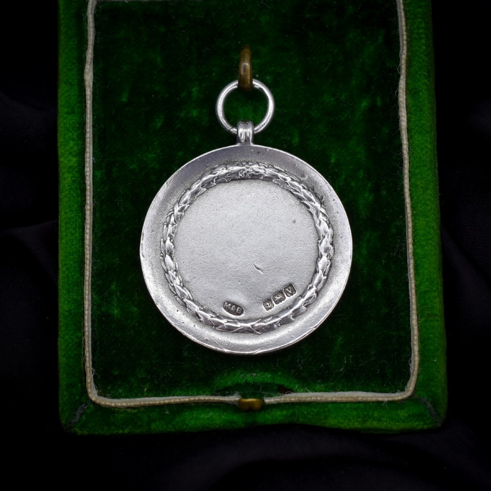 A circular silver medallion featuring a golfer rendered in relief mid-swing with a suspension ring attached to the top. View III