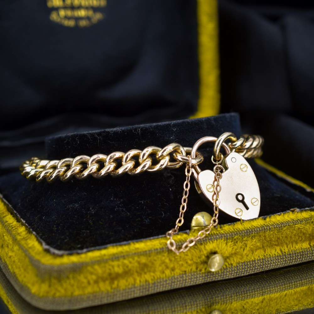 An antique 9ct yellow gold curb link chain bracelet fitted with a heart-shaped padlock clasp and an attached safety chain. View III
