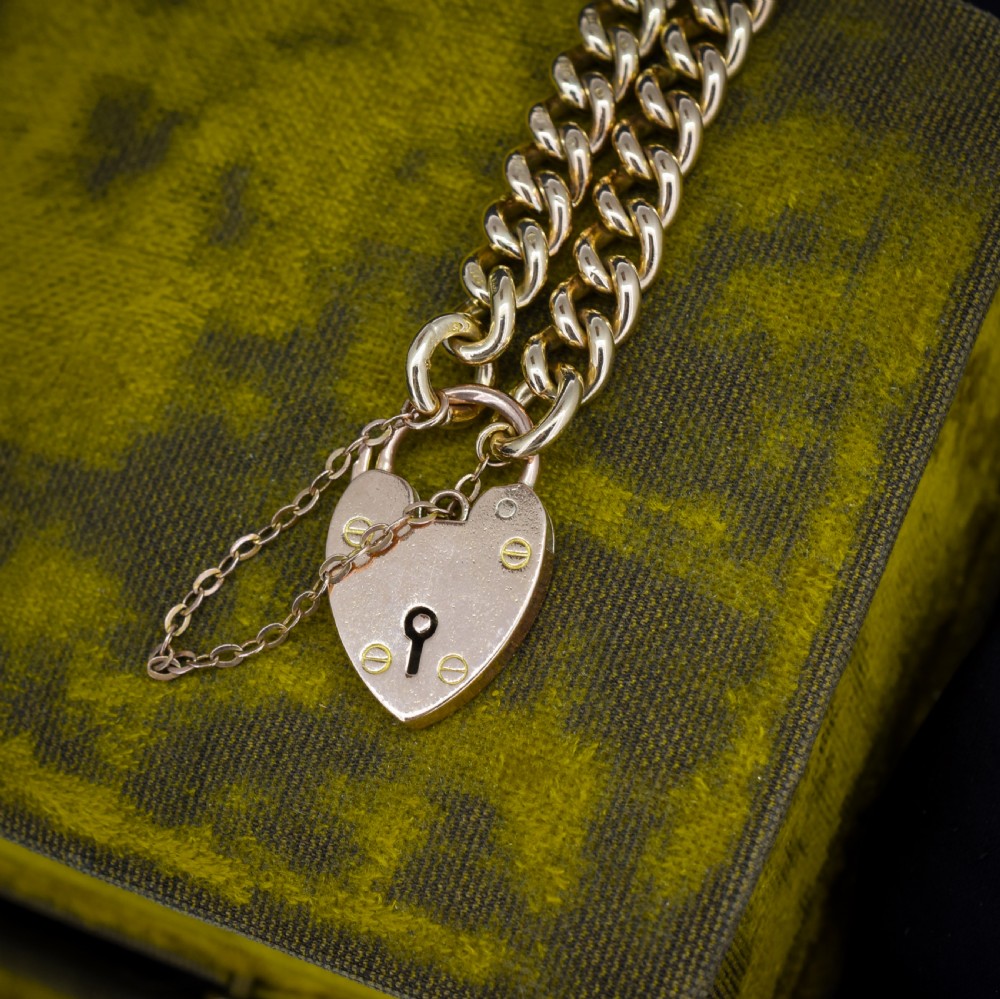 An antique 9ct yellow gold curb link chain bracelet fitted with a heart-shaped padlock clasp and an attached safety chain. View VII