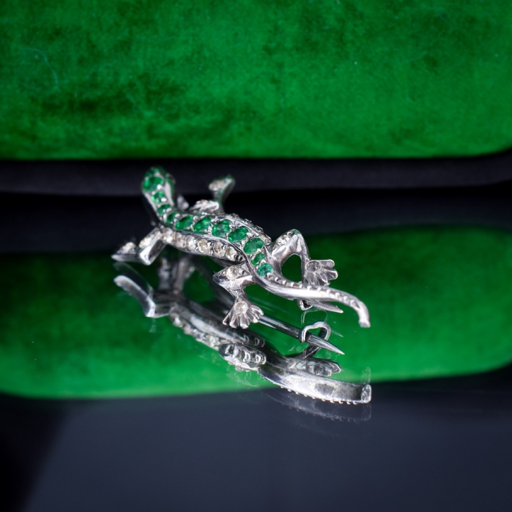 A Victorian silver lizard brooch set with green and clear paste stones. View IV