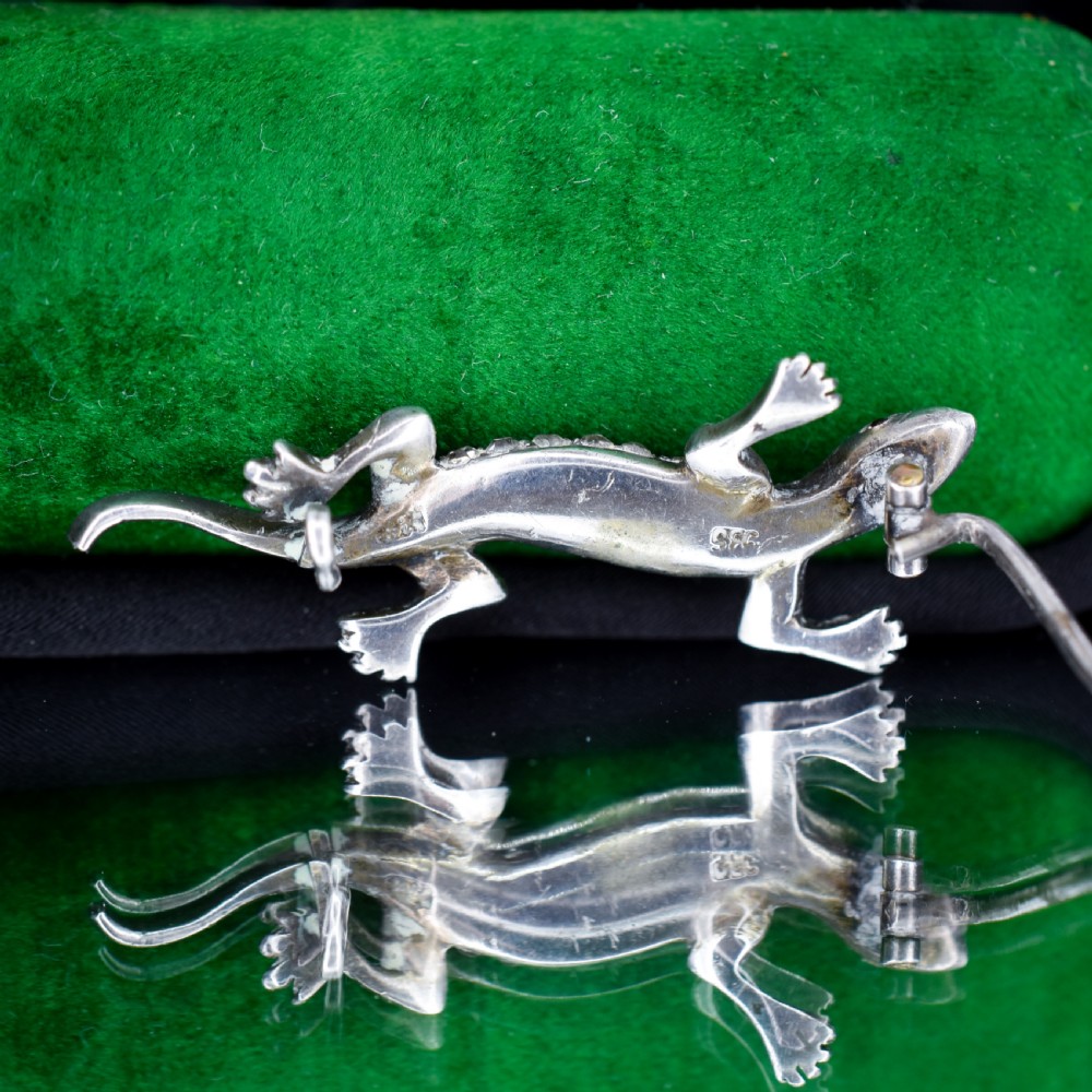 A Victorian silver lizard brooch set with green and clear paste stones. View VI