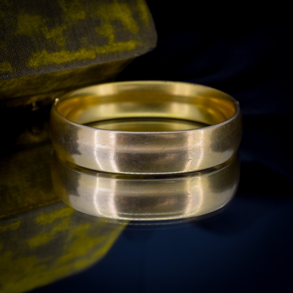 An antique gold-filled hinged bangle decorated with raised floral motifs with red and clear paste stone centres. View VIII