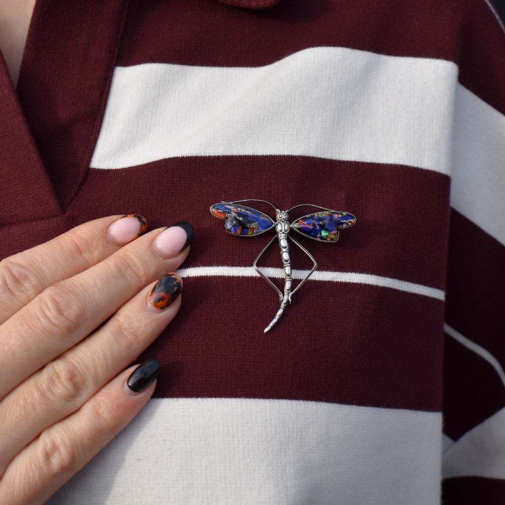 An Art Deco sterling silver dragonfly brooch featuring a stylized segmented body and iridescent blue and orange wing inserts. View IV