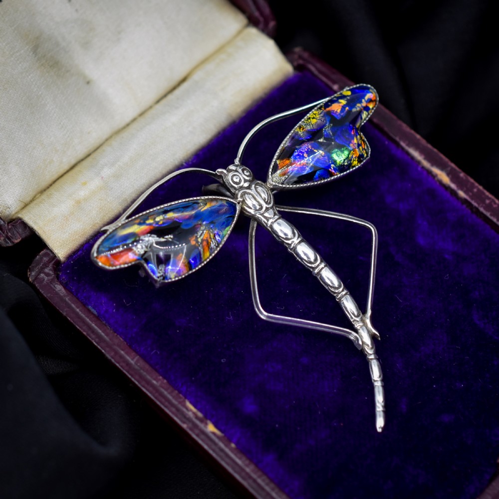 An Art Deco sterling silver dragonfly brooch featuring a stylized segmented body and iridescent blue and orange wing inserts. View V