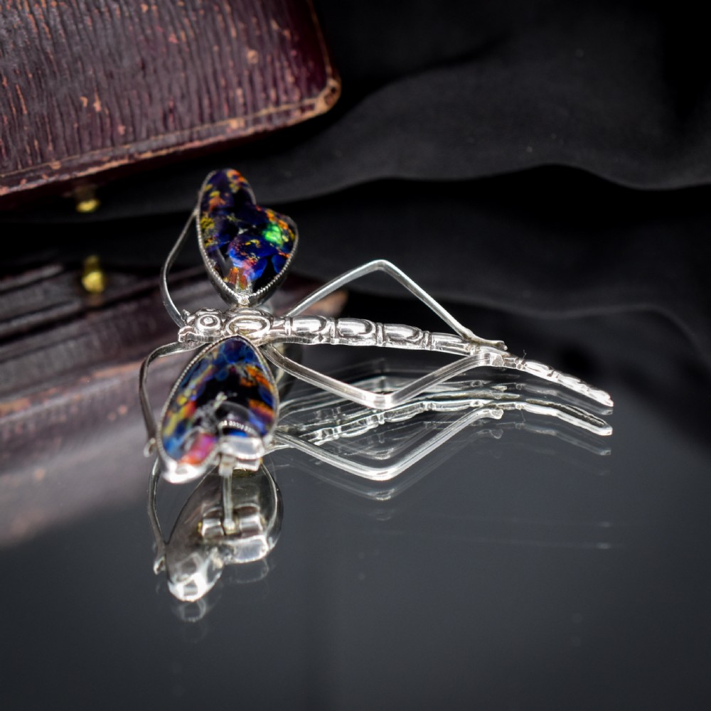 An Art Deco sterling silver dragonfly brooch featuring a stylized segmented body and iridescent blue and orange wing inserts. View VI