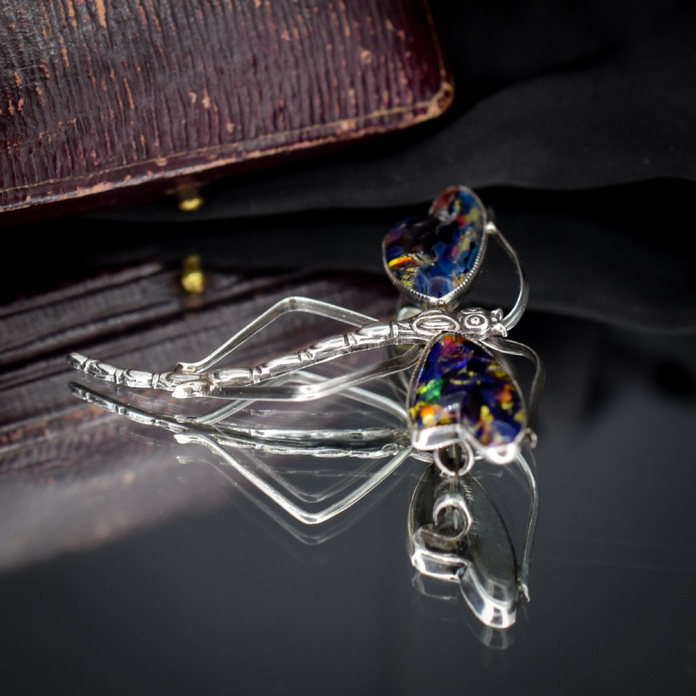 An Art Deco sterling silver dragonfly brooch featuring a stylized segmented body and iridescent blue and orange wing inserts. View VII