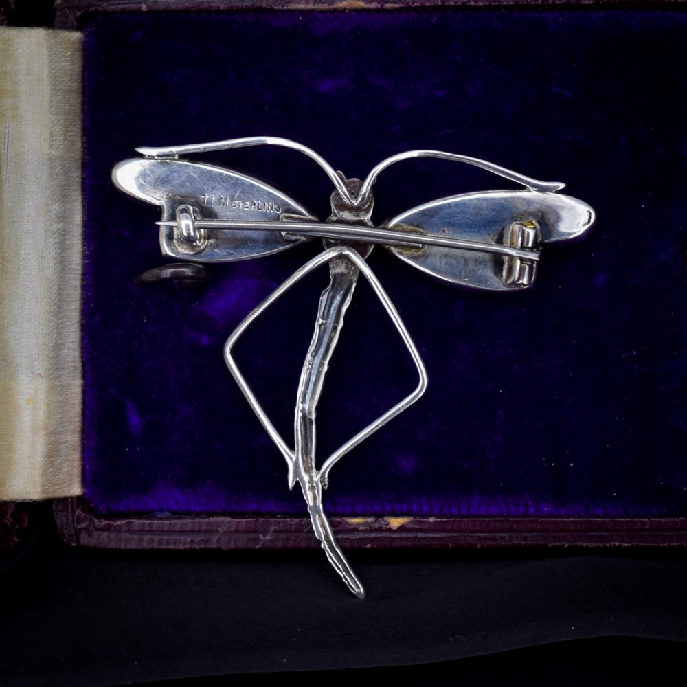 An Art Deco sterling silver dragonfly brooch featuring a stylized segmented body and iridescent blue and orange wing inserts. View IX