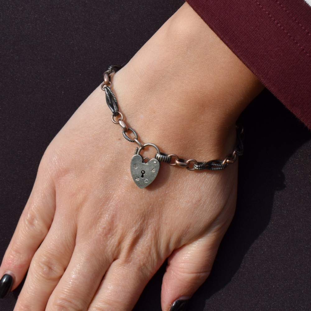 An antique silver and rose gold link bracelet featuring niello patterned twist links and a silver heart-shaped padlock clasp. View II
