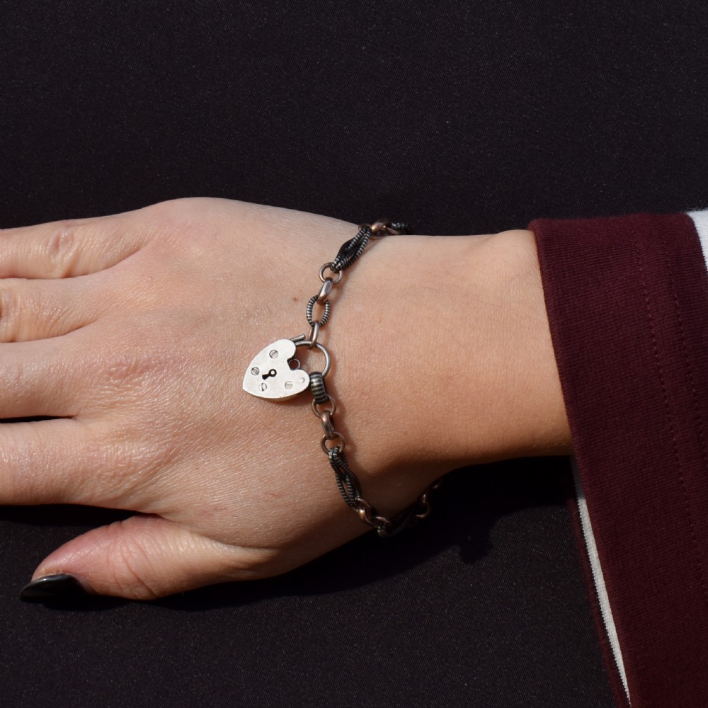 An antique silver and rose gold link bracelet featuring niello patterned twist links and a silver heart-shaped padlock clasp. View III