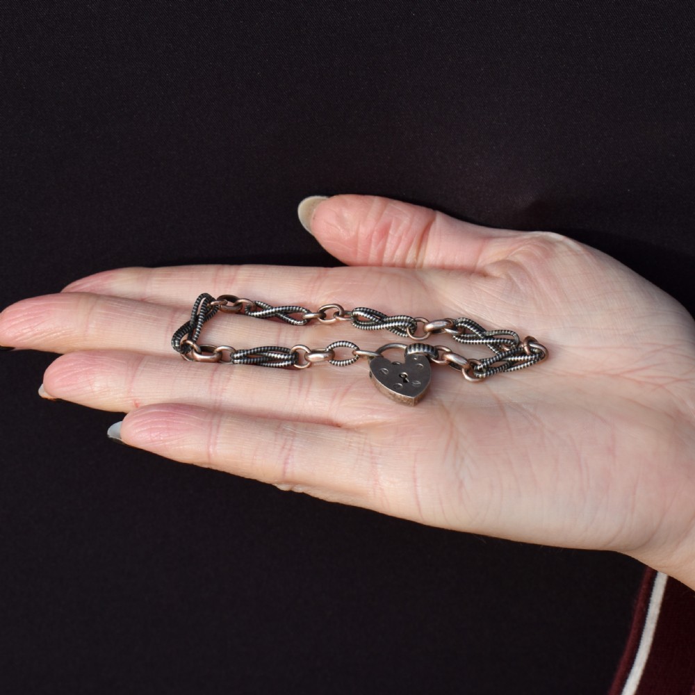 An antique silver and rose gold link bracelet featuring niello patterned twist links and a silver heart-shaped padlock clasp. View VII