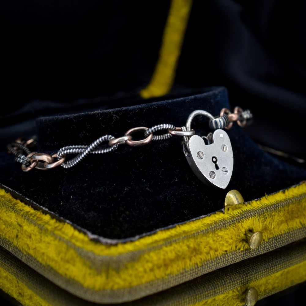An antique silver and rose gold link bracelet featuring niello patterned twist links and a silver heart-shaped padlock clasp. View VIII