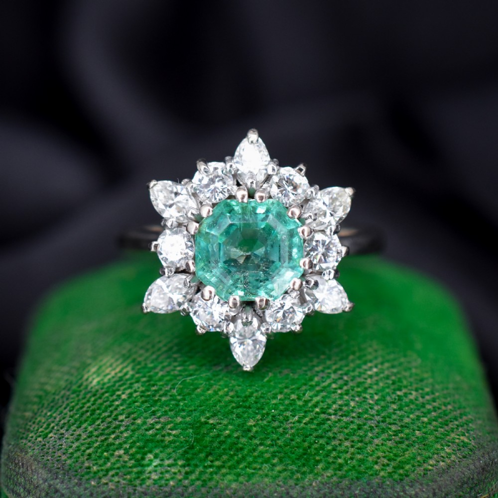 A vintage gold cluster ring featuring a central octagonal green emerald surrounded by a snowflake halo of round and marquise diamonds.
