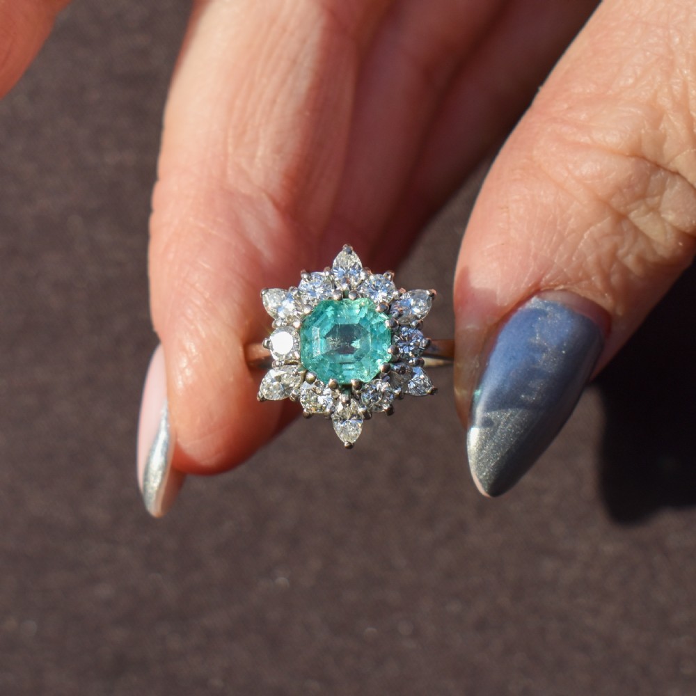 A vintage gold cluster ring featuring a central octagonal green emerald surrounded by a snowflake halo of round and marquise diamonds. View V