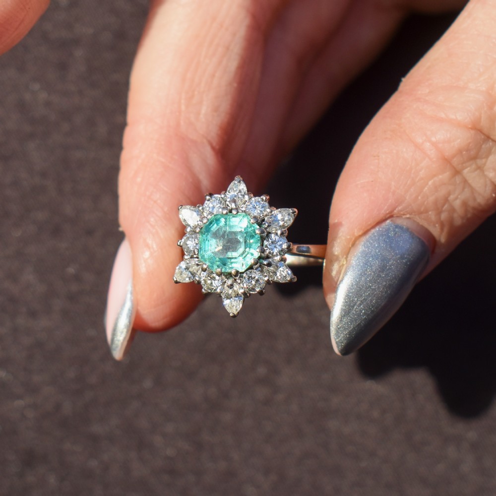 A vintage gold cluster ring featuring a central octagonal green emerald surrounded by a snowflake halo of round and marquise diamonds. View VII