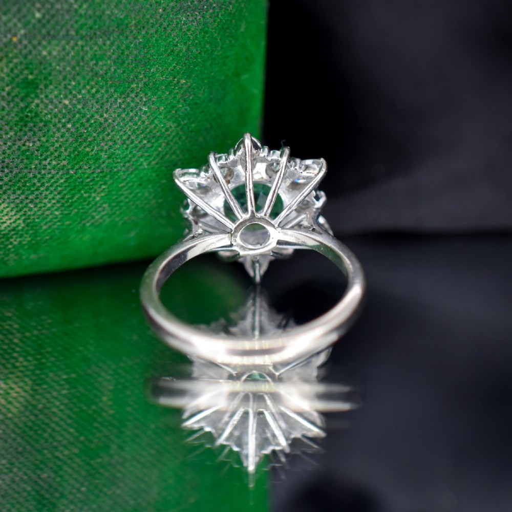 A vintage gold cluster ring featuring a central octagonal green emerald surrounded by a snowflake halo of round and marquise diamonds. View VIII