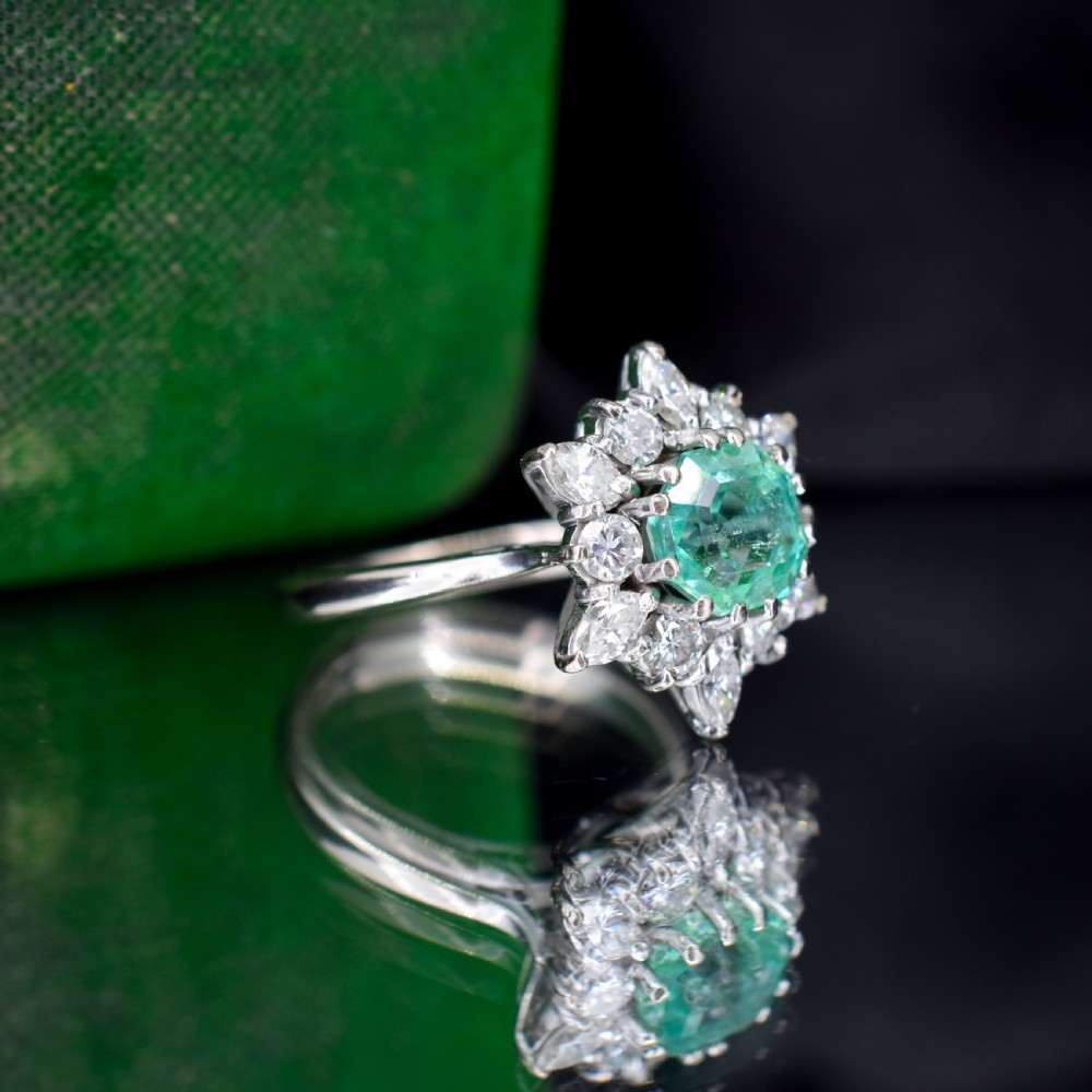 A vintage gold cluster ring featuring a central octagonal green emerald surrounded by a snowflake halo of round and marquise diamonds. View IX