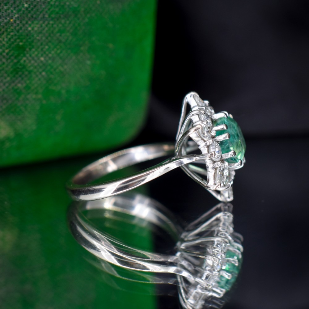 A vintage gold cluster ring featuring a central octagonal green emerald surrounded by a snowflake halo of round and marquise diamonds. View X