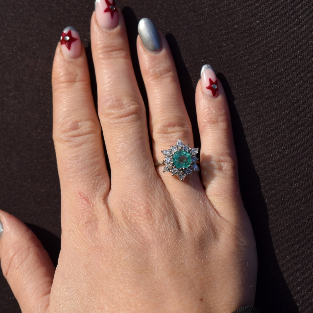 A vintage gold cluster ring featuring a central octagonal green emerald surrounded by a snowflake halo of round and marquise diamonds. View XII