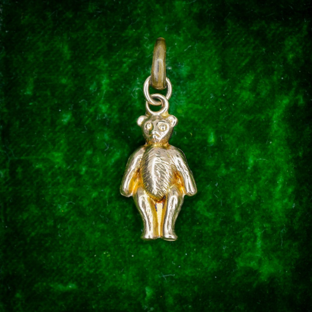 An antique 9ct gold teddy bear charm featuring a textured fur surface and a gold suspension loop.