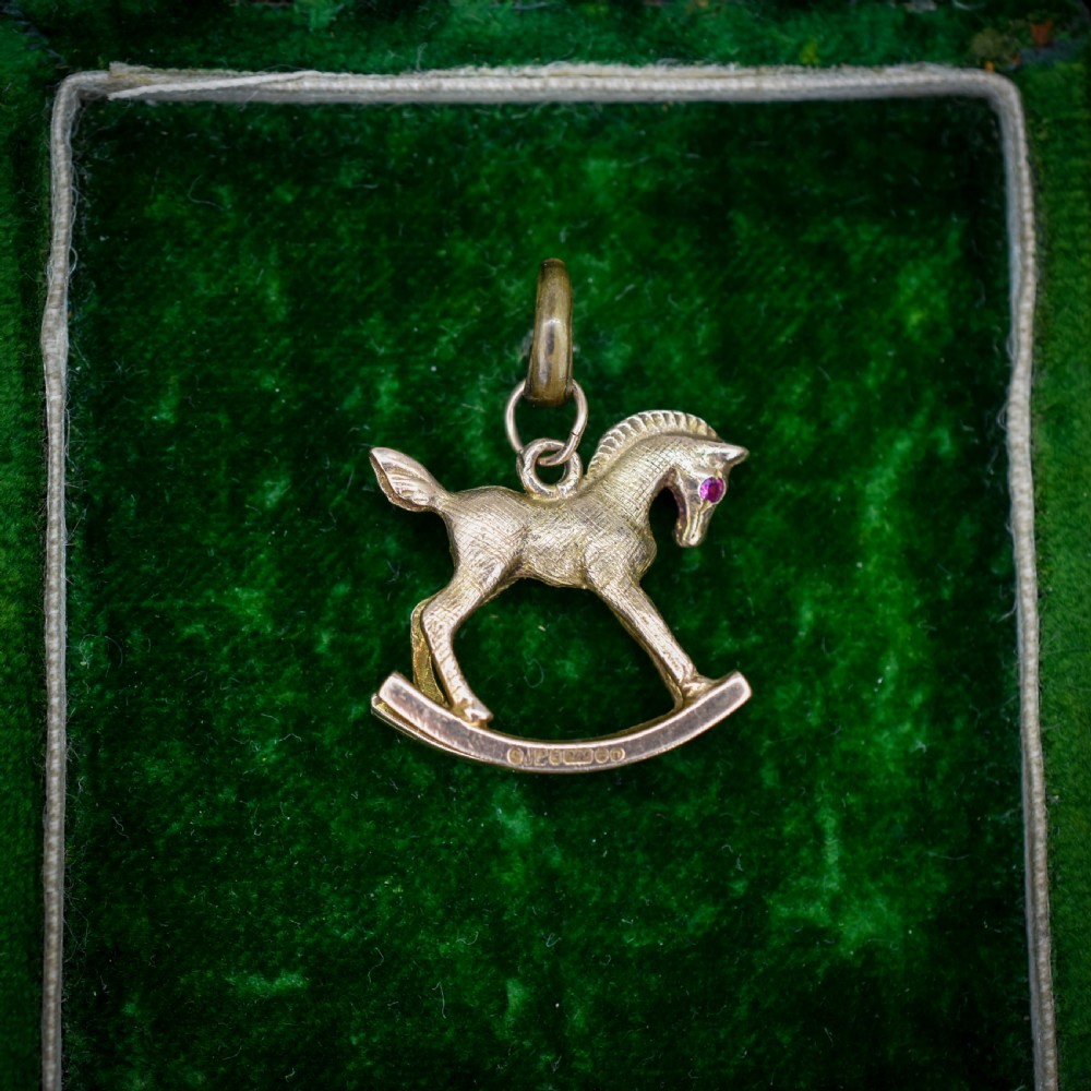 A 9ct yellow gold rocking horse charm featuring textured metalwork and a small pink gemstone eye. View III